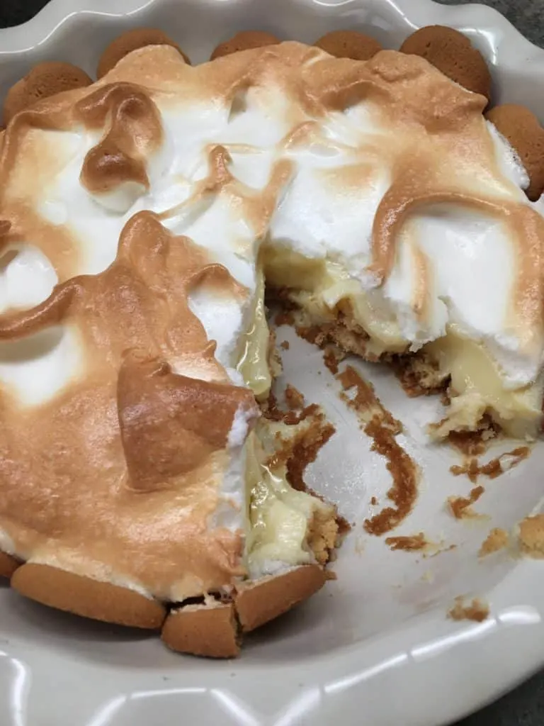 Lemon meringue pie in a pie shell. The pie has Nilla Wafers for the pie crust. There's a slice taken out.