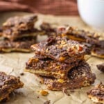 Chocolate toffee broken up in pieces on some parchment paper.