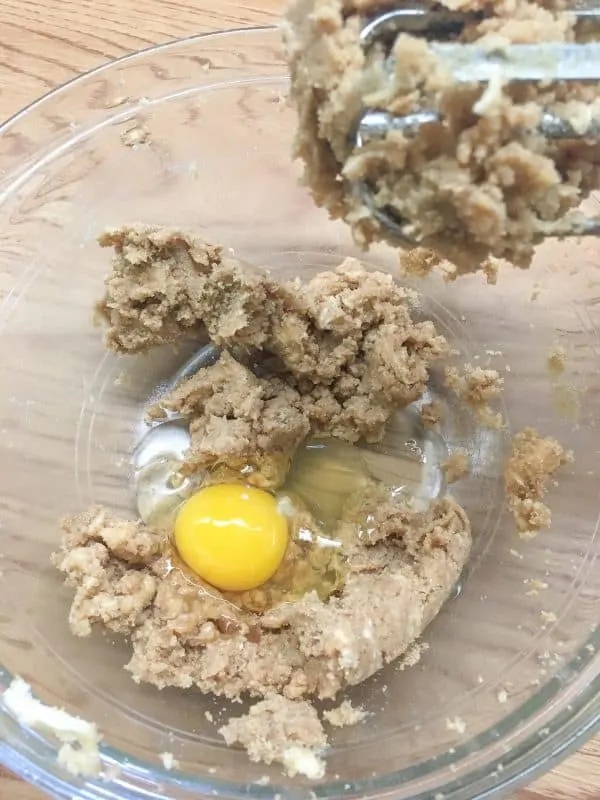 Ingredients for chocolate chip cookies in a clear glass mixing bowl.