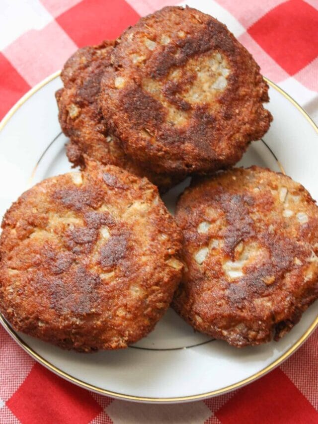 Salmon patties on a white plate with a checked red and white tablecloth