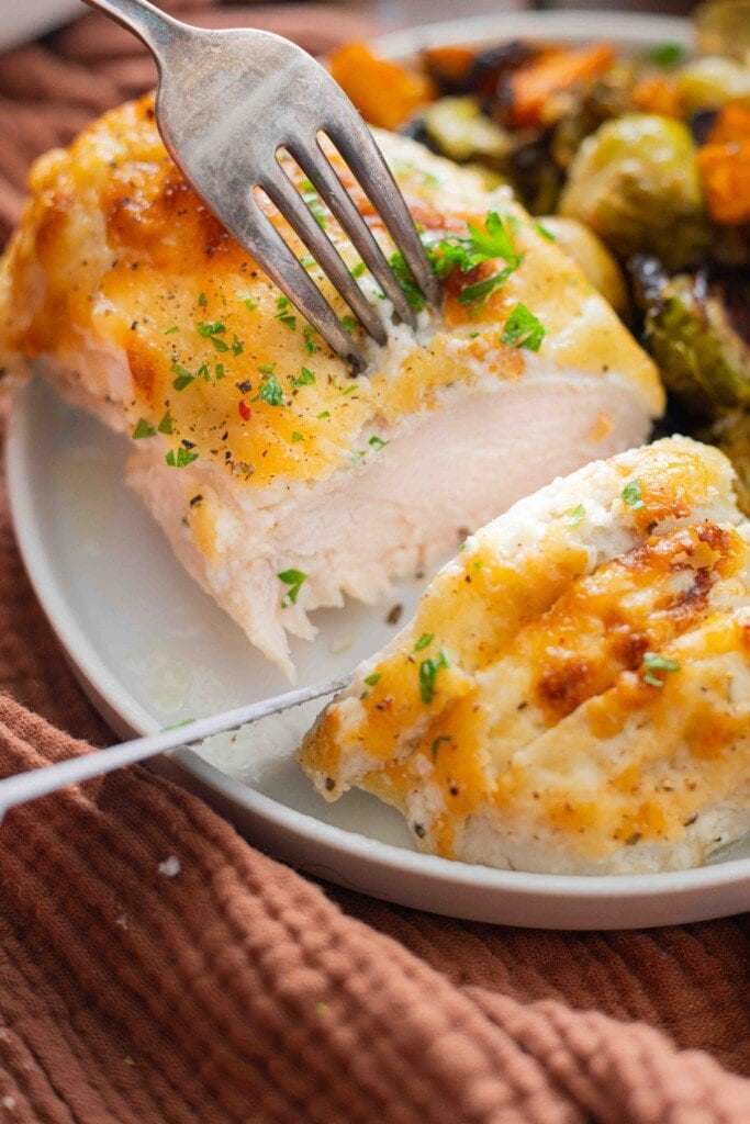 Tender baked chicken breast cut open with a knife.