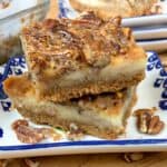 Pecan pie cheesecake bars stacked on a plate