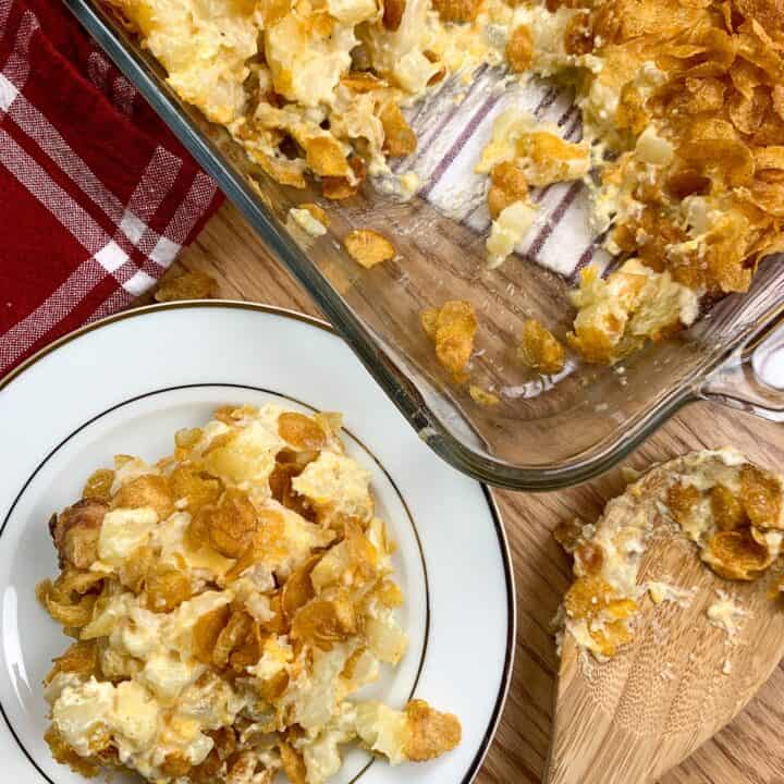 Funeral potatoes on a plate next to a casserole dish