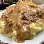 Crock pot pork shoulder on a plate with gravy