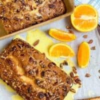 Two loaves of banana nut bread on a counter with orange slices