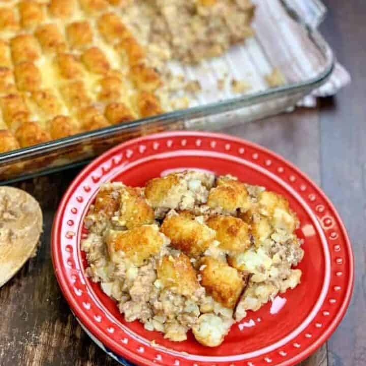 Tater tot casserole on a red plate next to a casserole dish