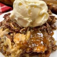 Pecan pie cobbler on a white plate with a scoop of ice cream
