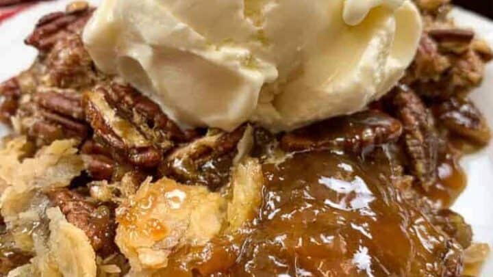 Pecan pie cobbler on a white plate with a scoop of ice cream