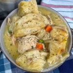 chicken and dumplings in a small brown bowl with bits of