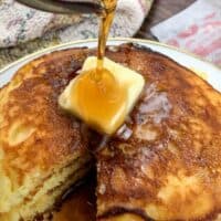 Pouring syrup over butter on Jiffy Cornbread Pancakes