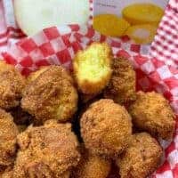 Hush puppies in a basket sitting next to a sweet onion