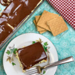 Eclair cake sitting on a white plate and blue placemat.