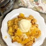 Pineapple dump cake with ice cream on a white plate.