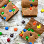 Cookie bars on a counter with M&Ms scattered.