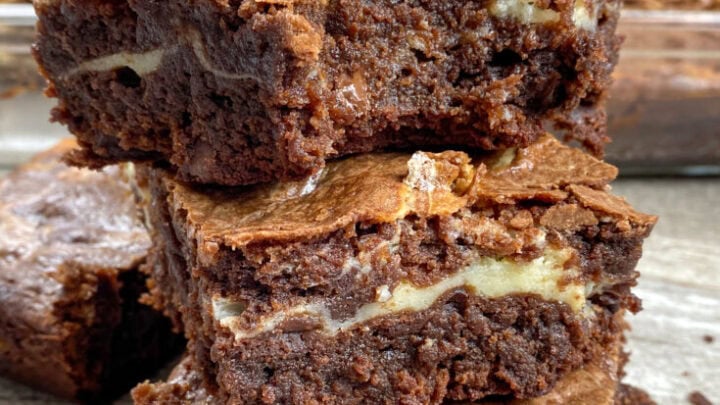 Cream cheese swirl brownies stacked on top of each other.