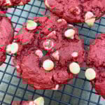 Red velvet cake mix cookies with white chocolate chips on a cooling wire rack.