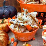 Halloween caramel popcorn in an orange cup with Trick-Or-Treat written on the outside.