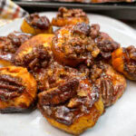 Glazed sweet potatoes with pecans on a white plate.