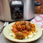 Pork sausage on a plate with veggies and mashed potatoes.