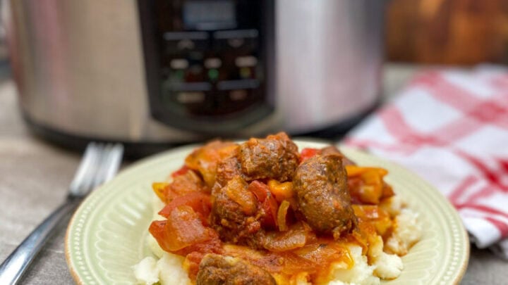 Pork sausage on a plate with veggies and mashed potatoes.