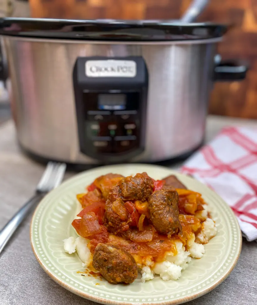 Crock Pot Sausage and Peppers Crock Pot sausage and peppers on a beige plate.