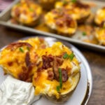 Twice baked potato on a plate with sour cream.