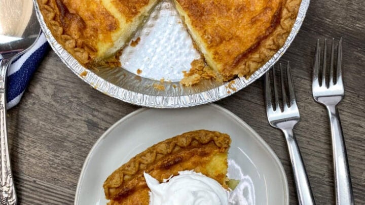 A slice of buttermilk pie on a white plate with whipped topping.