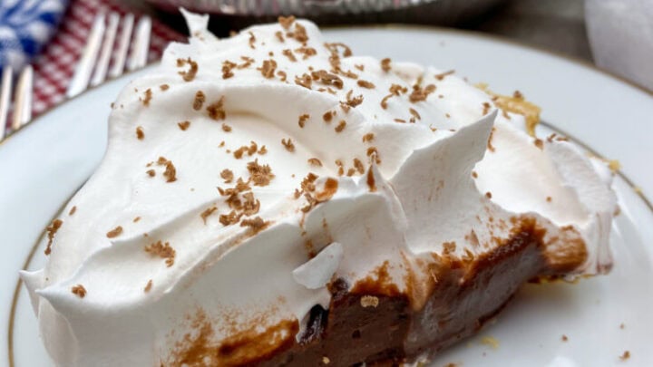 A slice of chocolate cream pie on a white plate.