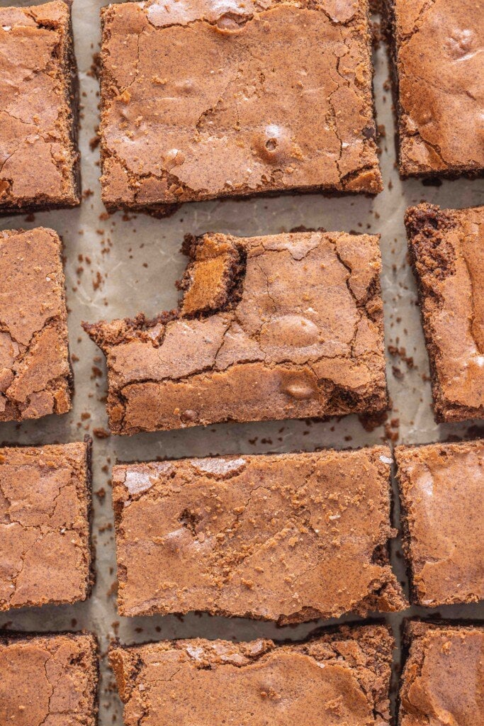 Brownies on the counter that are sliced. Once of the brownies in the center has a bite taken out of it.