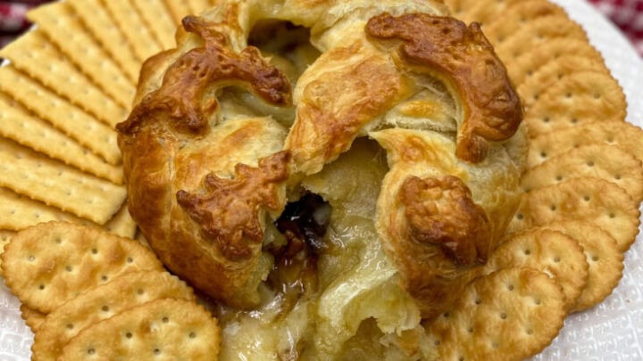 Baked brie on a white plate with crackers.