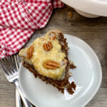 A slice of chocolate cake with pecans on top.