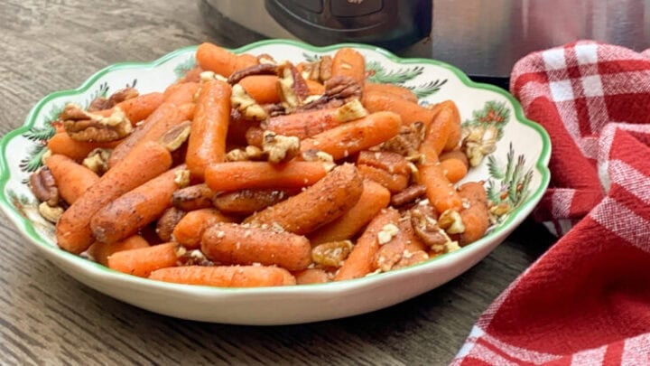 Cooked baby carrots in a bowl with pecans.