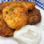 Mashed potato cakes on a plate with sour cream.