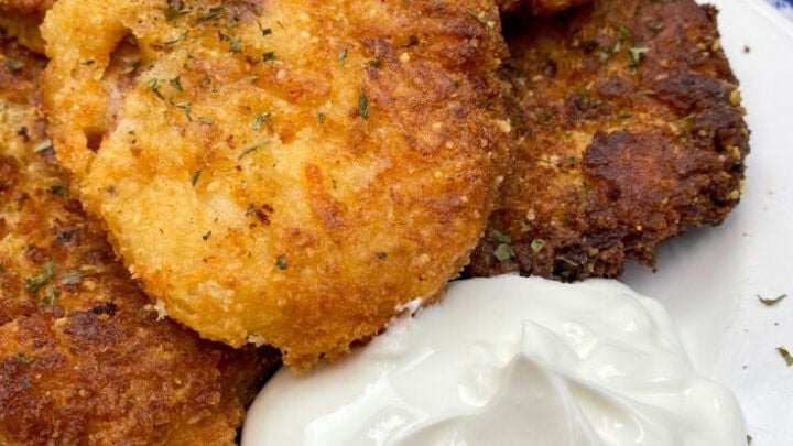 Mashed potato cakes on a plate with sour cream.