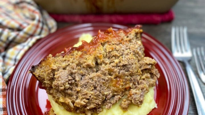 Traditional meatloaf recipe on a red plate with mashed potatoes.