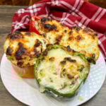 Four sausage stuffed peppers on a white plate.