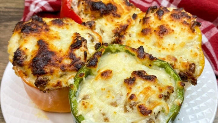 Four sausage stuffed peppers on a white plate.