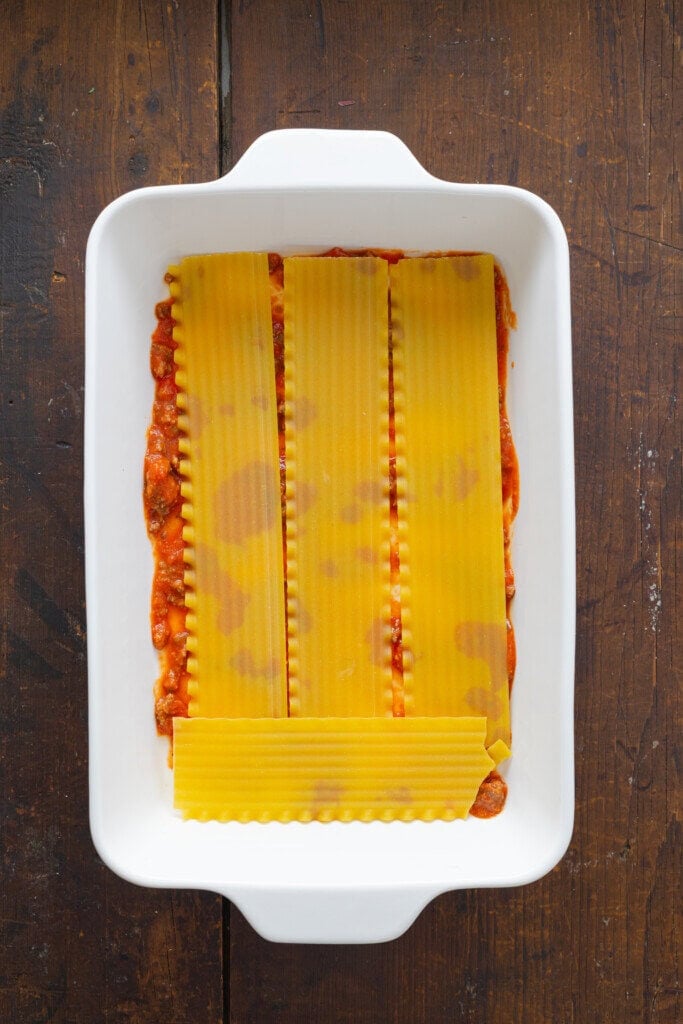 Layering noodles and spaghetti sauce in a casserole dish.