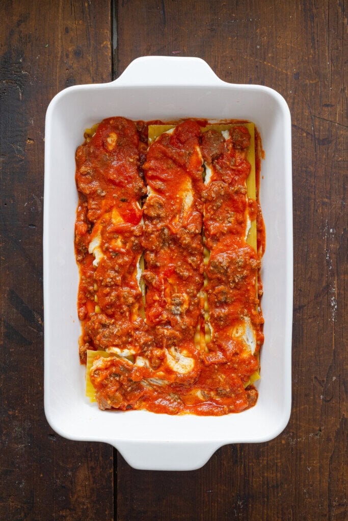 Beef, spaghetti sauce, and noodles layered in a baking dish.
