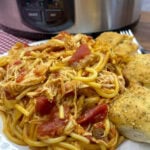 Italian chicken with spaghetti noodles and cheese bread on the side.