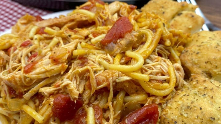 Italian chicken with spaghetti noodles and cheese bread on the side.