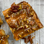 Praline pecan cheesecake bars on a cooling rack.