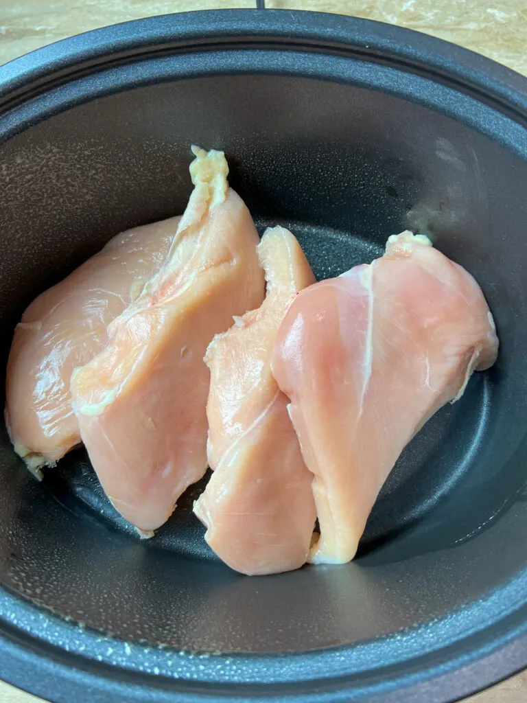 Raw chicken in a Crock Pot covered with non stick spray.