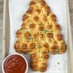 Christmas tree appetizer on a baking pan with some marinara sauce on the side in a bowl.