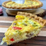 A slice of egg quiche sitting on a cutting board.