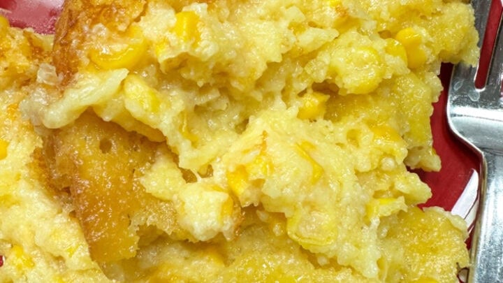 Cooked Crock Pot corn pudding on a red plate. There is a fork sitting on the right side of the plate.