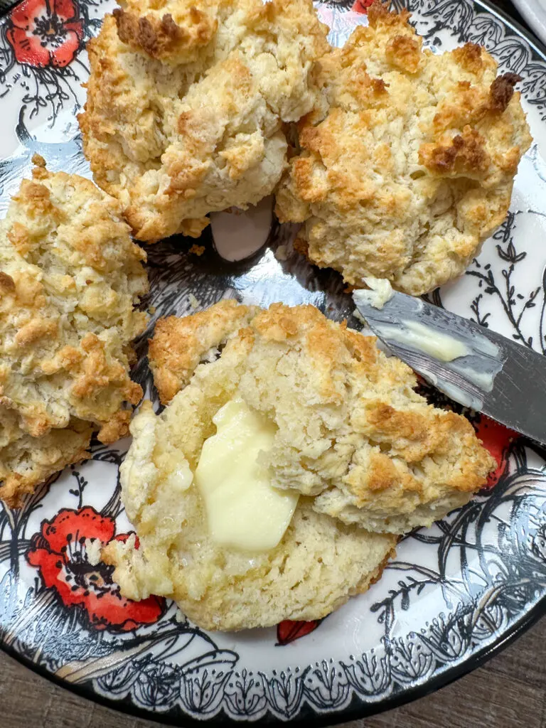 A biscuit sliced in half with some butter on top.