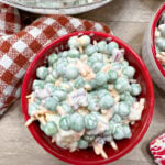 English pea salad in a red bowl. There is a large mixing bowl behind the bowl.