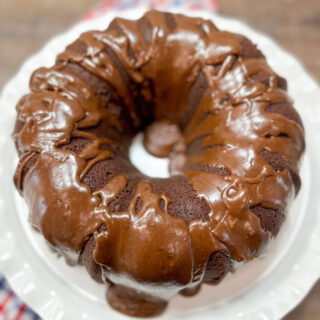 Chocolate cake covered in chocolate frosting. The cake is on a cake plate.