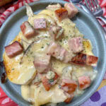 Ham and au gratin potatoes on a blue plate.